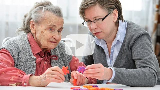 Elderly person with support person working on a jigsaw puzzle